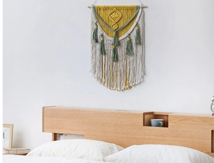 Detailed view of handmade macrame wall hanging with mustard yellow and green fringe tassels
