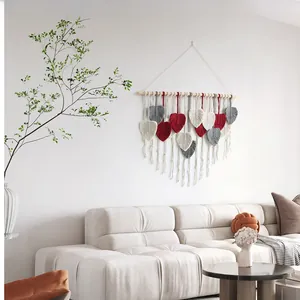 Detail of bohemian woven leaf wall hanging with red and grey cotton rope on a wood rod