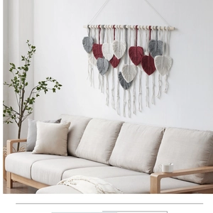 Close-up of handmade macrame leaf tapestry in white, grey, and burgundy yarn