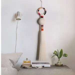 Detail of hand-woven wall hanging with colorful stripes and long tassels for home decor