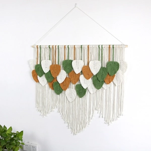 Handmade Bohemian wall hanging featuring woven cotton leaves on a natural wood rod