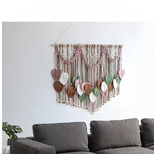 Detail of bohemian leaf tapestry with pink and green macrame on a wooden bar