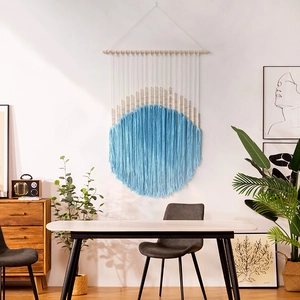 Bohemian woven tapestry with circular blue fringe and wood beads on a white wall decor