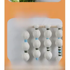 Detailed view of bohemian wall hanging featuring cotton spheres and wood rod