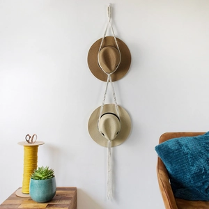 Handmade bohemian macrame hat holder in white cotton rope with tassels for wall display