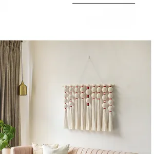 Detail of bohemian woven tapestry with pom-pom knots, red stitching and cotton fringe