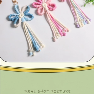 Detailed macro of handmade crochet flower charm with cotton tassels and pearl beads
