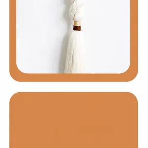 Detail of handcrafted cream macrame tassel with decorative brown and gold thread knots