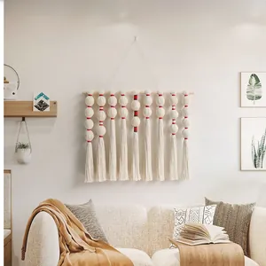 Detail view of handmade macrame wall hanging with pompons and tassels for boho home decor