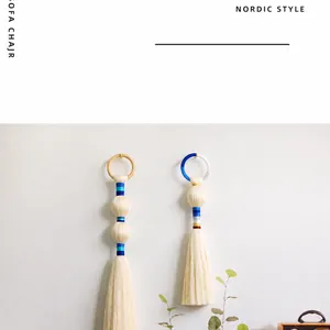 Detail of handcrafted Nordic macrame wall hanging with cotton tassels and blue thread accents