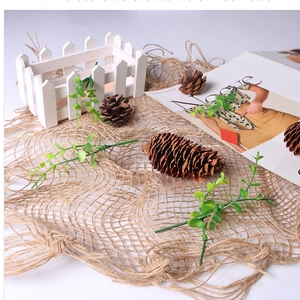 Macro shot of natural woven jute mat set with faux greenery and pine cones for photography