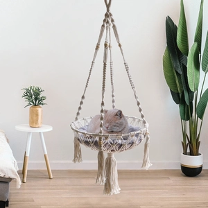 Handmade bohemian macrame cat hammock with decorative tassels and a soft purple cushion