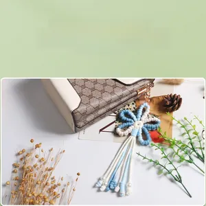 Detail of handmade knitted blue flower keychain with tassel and white pearl bead