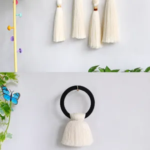 Detail of white silk tassels on a black elastic hair tie with metallic rings
