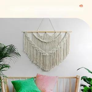 Detail of bohemian handmade woven wall tapestry with cotton tassels and wooden rod