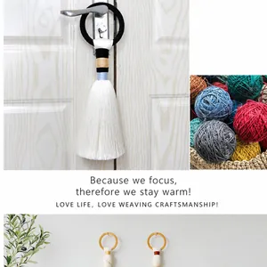 Macro detail of handmade Nordic tassel wall hanging with woven knot on a white door handle