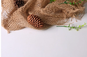 Detail of hand-woven brown hemp rope mat photography prop with natural pine cones and plants