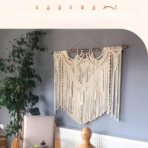 Detailed close-up of bohemian hand-woven cotton tapestry with geometric fringe and wood rod