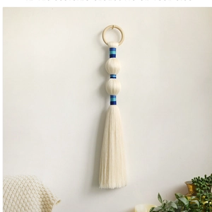 Detail of Nordic boho wall hanging with ivory fringe and blue thread accents