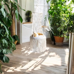 Detail of hand-woven macrame cat hammock featuring long tassels and soft plush cushion