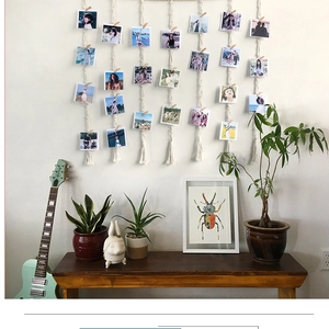 Detail of hand-woven cotton wall decor with tassels and wooden clips for photos