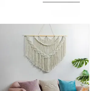 Detail of bohemian handmade woven wall tapestry with tassels on a wooden rod