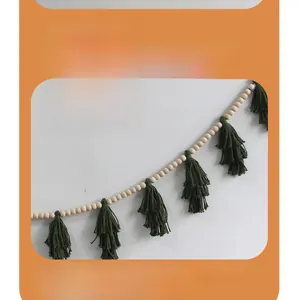 Detail of wooden beads and dark green layered cotton tassels for wall hanging decor