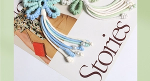 Detailed view of handmade woven flower keychain with macaron cotton cords and white pearls