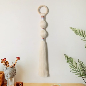 Macro detail of Nordic woven wall hanging with cotton fringe and decorative spheres