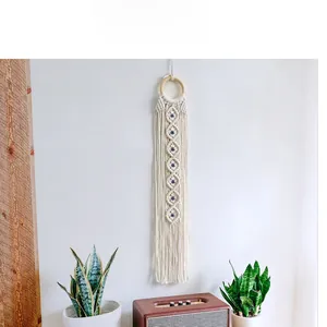 Macro shot of boho woven cotton wall hanging with wooden ring and blue beads decor