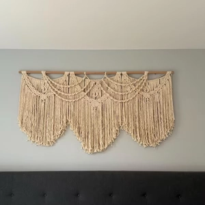 Detail of handmade bohemian wall hanging featuring intricate woven cotton patterns and tassels