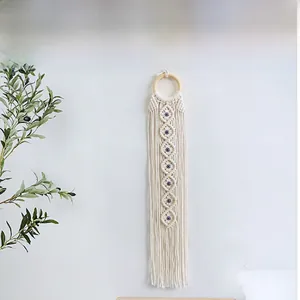 Detail of handmade evil eye macrame wall hanging with cotton fringe and wood ring