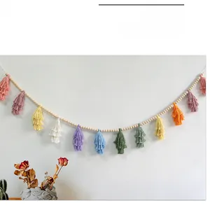 Detail of colorful cotton tassels with natural wood beads on a white wall