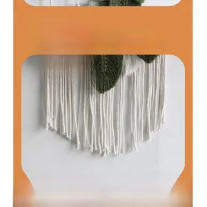 Dettaglio dell'arazzo fatto a mano con foglie verdi e nappe di cotone bianco per pareti