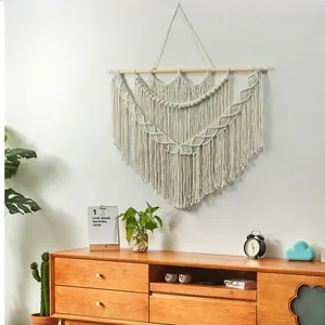 Close-up of bohemian hand-woven cotton macrame wall hanging with wooden pole and fringe