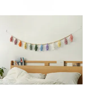 Detail of colorful boho tassel garland with wooden beads on a white wall