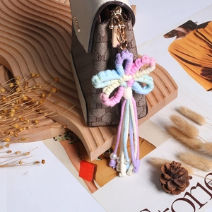 Handmade woven macrame flower charm keychain with tassels and pearls on a stylish bag
