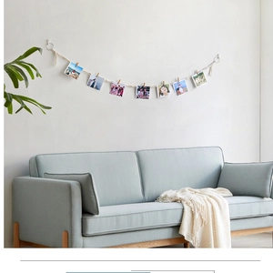 Detailed view of bohemian hand-woven cotton cord photo display with mini wooden clips on wall