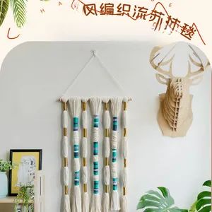 Detail of bohemian handmade woven wall hanging with colorful cotton tassels and wooden rod