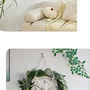 Detail of bohemian hand-woven wall hanging with eucalyptus leaves and plush pillows