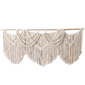 Handmade macrame wall hanging featuring bohemian cotton rope fringe and wooden support rod