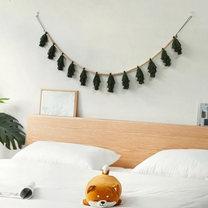 Nordic wooden bead garland with dark green tassels hanging on a bedroom wall
