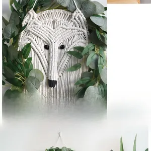 Close-up of handmade macramé fox wall hanging with cotton weaving and green leaves
