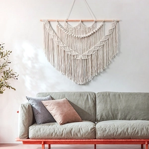 Bohemian hand-woven macrame wall hanging with geometric patterns and long tassels over a sofa