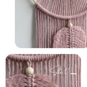 Detail of pink hand-woven bohemian wall hanging with cotton tassels and wooden beads