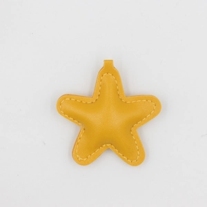 Détail d'un porte-clés en cuir PU jaune en forme d'étoile avec coutures précises
