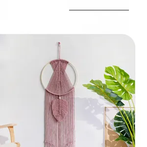 Detail of dusty pink macrame wall hanging with leaf pattern on a boho style wooden frame