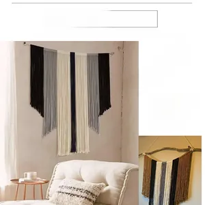 Détail d'une tapisserie bohème avec glands noirs, gris et crème sur une tige en bois
