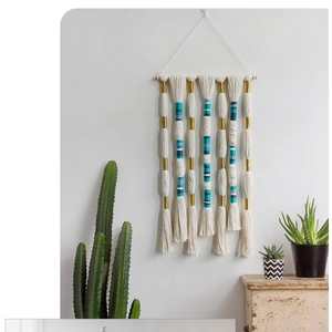 Detail of bohemian wall hanging with colorful thread accents on white cotton fringe