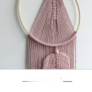 Detailed close-up of pink handmade macrame wall hanging with wooden ring and cotton cords